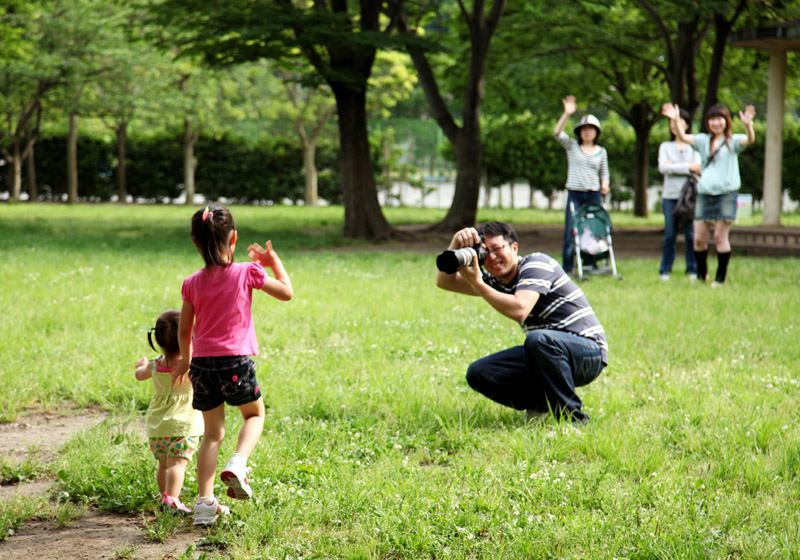 公園で姉妹を撮影するカメラマン